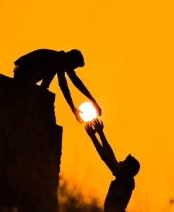 Silhouette of two people, reaching for the sun, symbolizing the hope and opportunity provided by the Second Chance Scholarship Foundation.