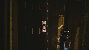 Police cruiser passing a truck n the left side on a highway. 